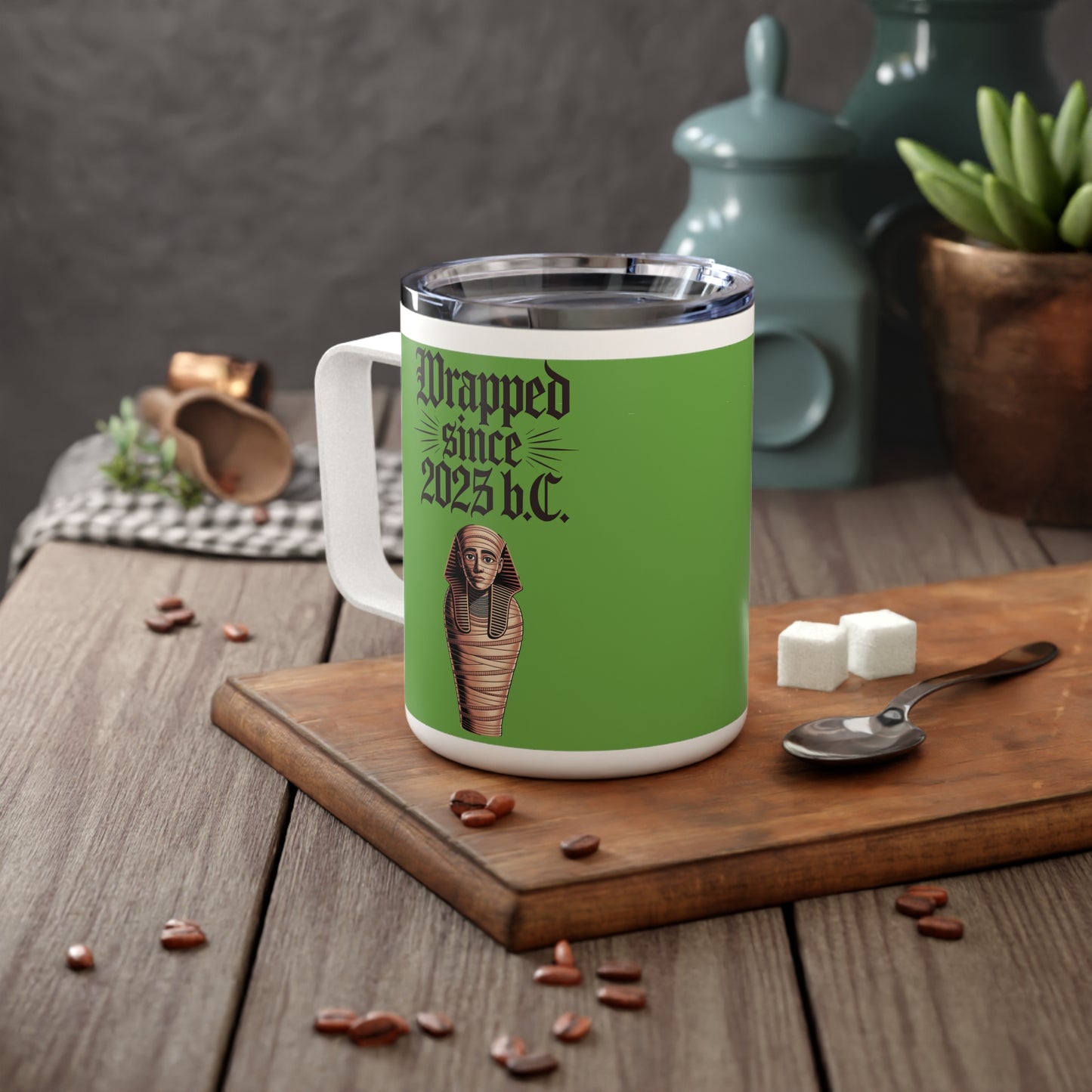 Wrapped Since 2025 B.C. stainless steel coffee mug on a table with autumn leaves on a board.